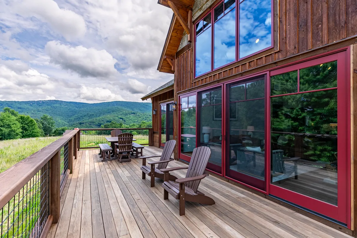 A wide deck with comfortable seating that overlooks a breathtaking mountain vista. Large windows from the house open onto the deck, blurring the line between indoor and outdoor living. The space is ideal for morning coffee, al fresco dining, or simply soaking in the serene view.