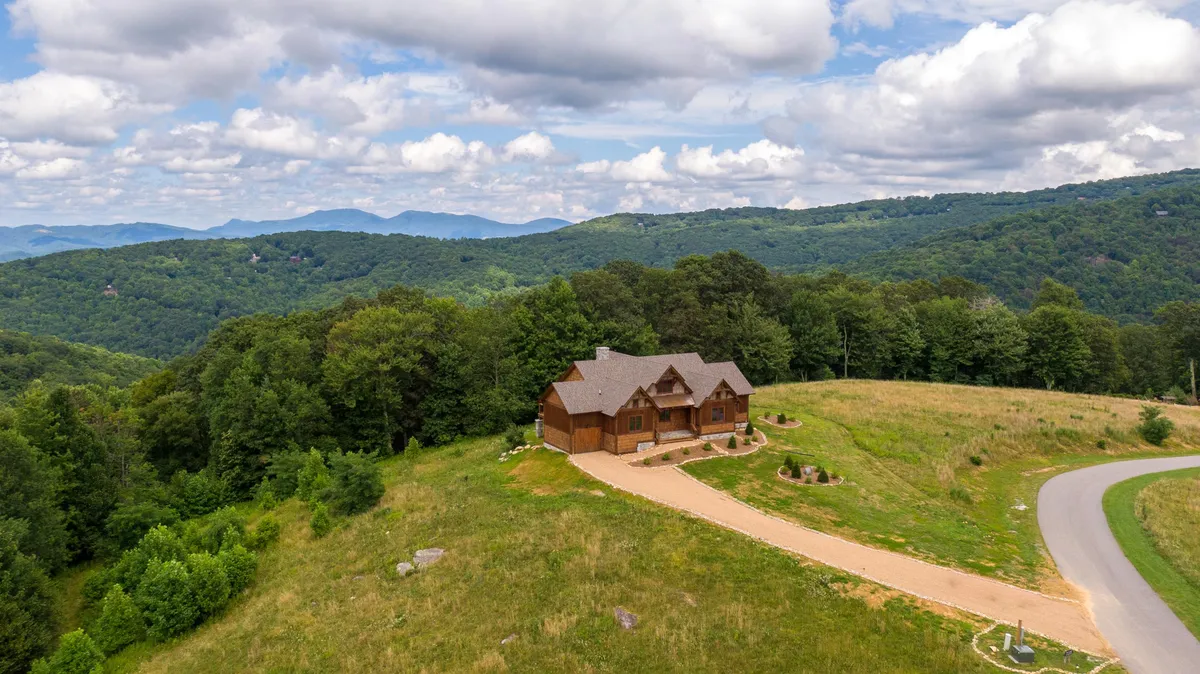 This exterior image showcases the wooden house with a landscaped yard set against a stunning mountain backdrop. The scene evokes tranquility and immersion in nature, hinting at the proximity of hiking trails, nature walks, and the peaceful environment surrounding the property.